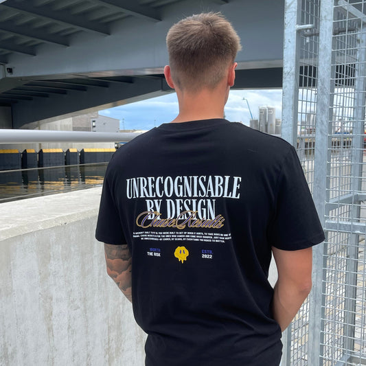 Person wearing a black t-shirt with text standing on a rooftop with cityscape in the background